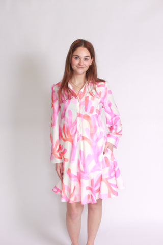 Woman wearing a pink orange and white watercolor coral dropwaist long sleeve dress