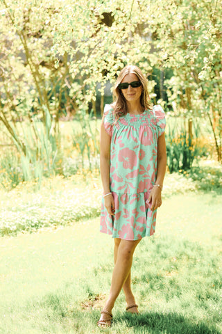 Woman wearing a pink and green dress standing in a garden