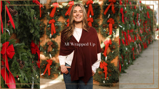 Woman standing in front of a row of Christmas wreaths with red ribbons, with 'All Wrapped Up' text overlay.