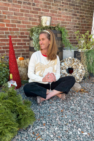 Woman sitting on a stone path with festive decorations including a wreath and gnome.