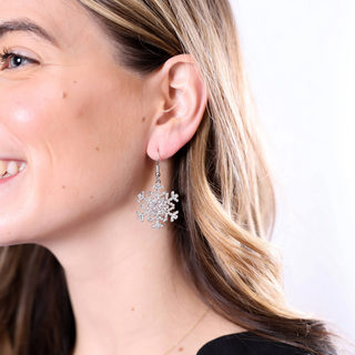 Woman wearing silver snowflake earrings with sparkling design