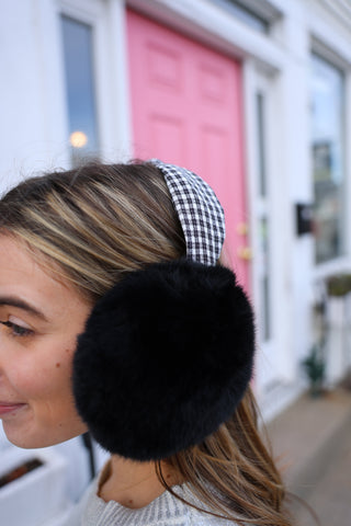 model wearing Black and white houndstooth earmuffs with black faux fur ear covering