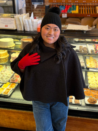 Woman wearing black Kristen Cape with black knit hat and red gloves