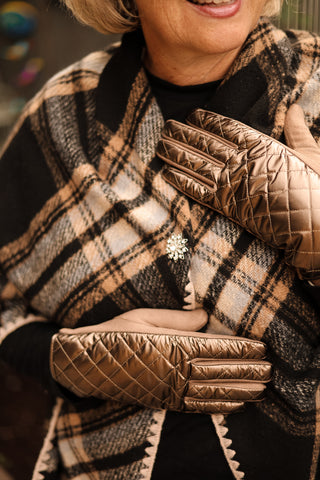 Person wearing a plaid claire wrap and quilted gloves with a snowflake magnetic brooch