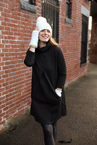 Lifestyle photo (model in white gloves): Woman wearing Tasmin faux fur fingerless gloves in white with matching pom pom beanie, styled for a chic fall/winter look.