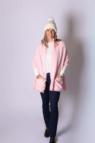 Woman wearing cream Gigi cable knit hat with light pink wrap and dark blue jeans