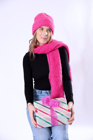 Woman wearing a pink hat and scarf holding a wrapped gift against a white background