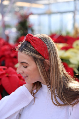 Woman wearing a red headband with poinsettias in the background