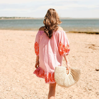 Woman wearing pink tunic with orange floral embroaidery 