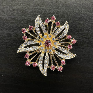 Gold decorative brooch in floral starburst shape with pink and clear rhinestones