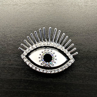 Evil eye brooch with silver accents, clear rhinestones, white enamel and a black gemstone