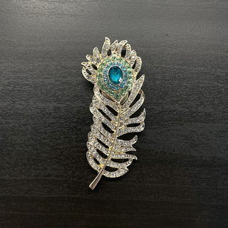 Gold brooch with feather design and clear and turquoise blue rhinestones