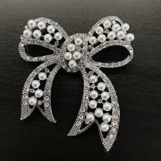 Silver bow-shaped magnetic brooch decorated with pearls and rhinestones