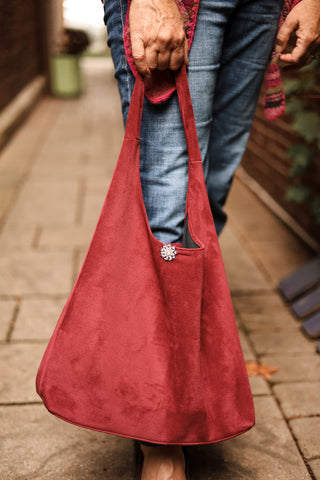 Red bag held by a person on a blurred outdoor background
