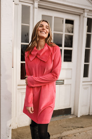 Woman wearing a pink coat standing outside a white building.