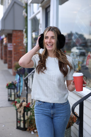 Woman wearing ear muffs and holding a red cup outdoors