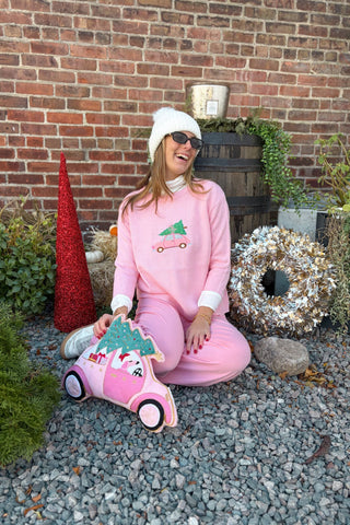 Person in pink outfit with scooter toy sitting on gravel against a brick wall.