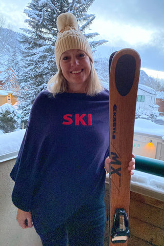 Women wearing a ski poncho while holding skis