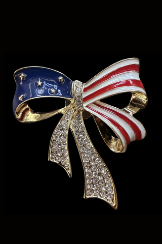 Gold bow brooch with American flag design on a black background