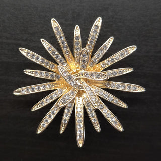Gold brooch with starburst design and rhinestones