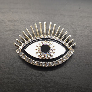 Evil eye brooch with gold accents, clear rhinestones, white enamel and a black gemstone