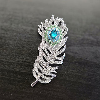 Silver brooch with feather design and clear and turquoise blue rhinestones