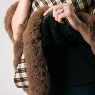 close up of plush underside of taupe and brown check plaid poncho with brown faux fur trim