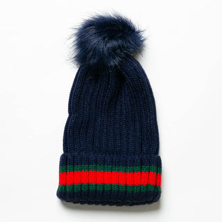 Navy knit hat with red and green stripe and navy faux fur pom pom.