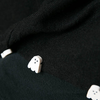 close up of black poncho with white ghost button trim
