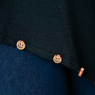 close up of black poncho with orange pumpkin button trim